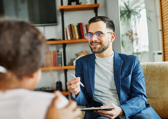 Portrait of a man psychologist talking to patient in his office in clinic. Giving support to a...