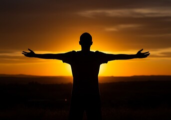 A man stands silhouetted with open arms at sunset