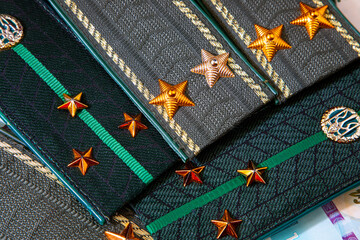 Shoulder straps and patches of Ukrainian military on the background of money. War in Ukraine