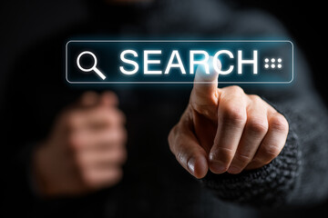 A teenager boy’s hand wearing casual clothes is touching glowing Search bar icon on a futuristic virtual screen