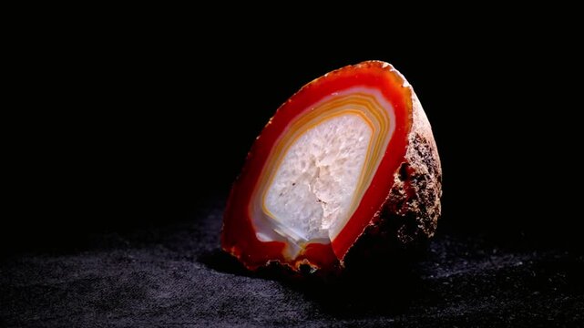 A polished slice of banded agate stone is isolated on black background