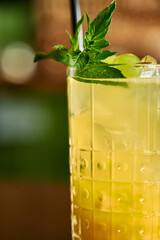 Refreshing lemon mint beverage in textured glass with straw