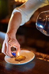 Bartender creating citrus aroma with lighter for unique cocktail experience