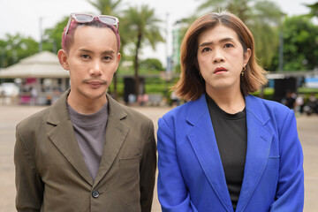 Confident non binary gay man with transgender businesswoman looking at camera outdoors in city