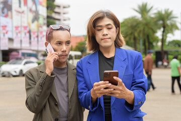 Gender diverse business coworker professionals using technology on city street