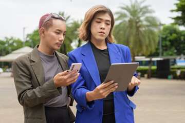 Gender diverse business coworker professionals using technology on city street