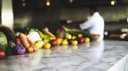 Fresh colorful vegetables on marble counter with blurred chef in kitchen background. Healthy organic produce, farm to table concept, culinary preparation, restaurant food photography