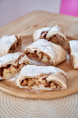Delicious homemade apple strudel with powdered sugar on wooden plate