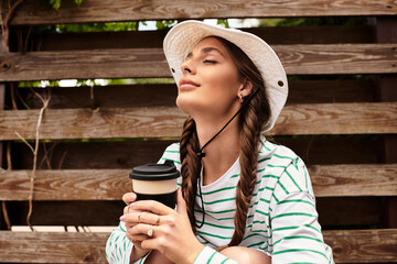 Relaxing under the warm sun, a woman enjoys her coffee at a serene park picnic