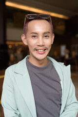 Non binary gay man with makeup sitting in cafe
