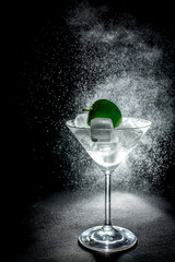 Fresh cocktail with green apple and ice cubes in a martini glass on black background
