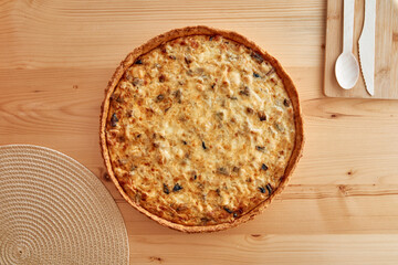 Savory baked quiche with mushrooms on wooden table with natural lighting