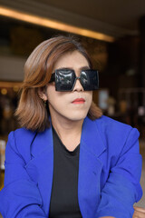 Confident Asian transgender woman in suit sitting alone in cafe