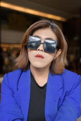Confident Asian transgender woman in suit sitting alone in cafe