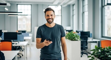 Smiling businessman holding a smartphone in a modern bright office with desks and plants