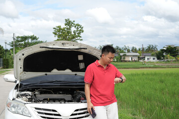 Depressed asian businessman is calling emergency help or car service center near broken car on road...