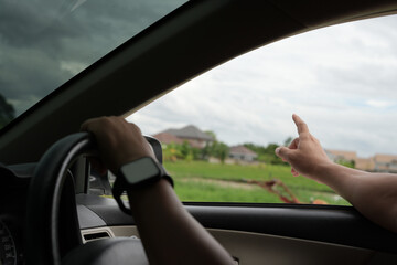 Fototapeta premium Close-up of the man's hand holding the steering wheel and looking for the fields and sunset, summer time and road trip for family leisure time.