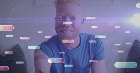 Smiling man in blue tee, gray headband sitting on sofa in living room with holographic codes