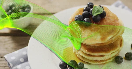 Showcasing stack of golden pancakes on wooden table, with blueberries, mint leaf and neon overlay © vectorfusionart