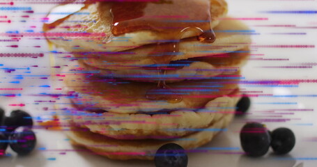 Pouring syrup over pancake stack sitting on kitchen countertop, with blueberries and glitch overlay