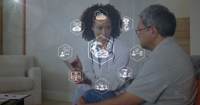 Female doctor in white coat discussing health with senior patient at home with tablet stethoscope