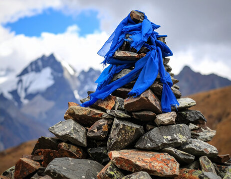 An "ovo" (sacred stone cairn) piled high on a mountain pass, adorned with blue khata scarves, for blessings.