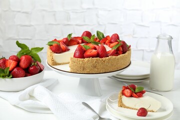 Delicious cheesecake with strawberries, mint and milk on white wooden table
