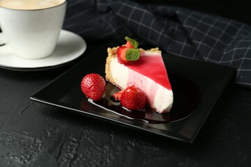 Piece of tasty cheesecake with strawberries, sauce, mint and coffee on black table, closeup