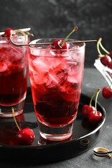 Tasty cherry soda with ice cubes and berries in glasses on grey table, closeup