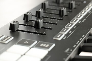 MIDI keyboard with faders on light background, closeup