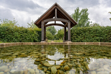 Pavilion with Reflecting Pool. A wooden pavilion is reflected in a shallow pool of clear stones....