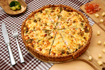 Cheesy broccoli salmon quiche with golden crust on checkered tablecloth for savory brunch ideas