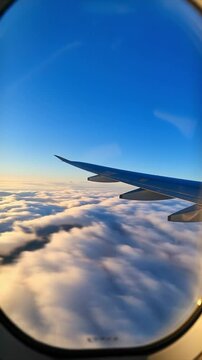 A View out of an airplane window onto a blue sky and clouds and sunlight moving fast