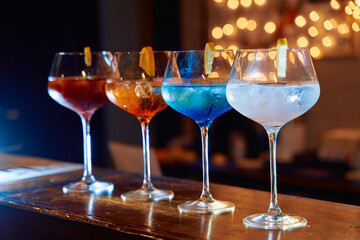 Colorful cocktails: red orange blue white drinks with lemon garnish on bar counter
