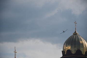 An aerobatic aircraft flies near the golden dome of an Orthodox church during an airshow event,...