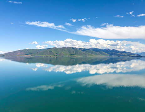 The serene waters of Lake Sevan, reflecting the surrounding verdant mountains and a cloud-strewn sky.