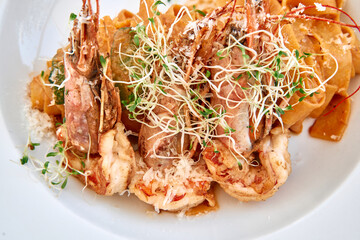 Gourmet prawn pasta with sprouts on white plate