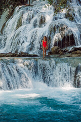 Woman posing on amazing waterfalls with blue water in Central Sulawesi