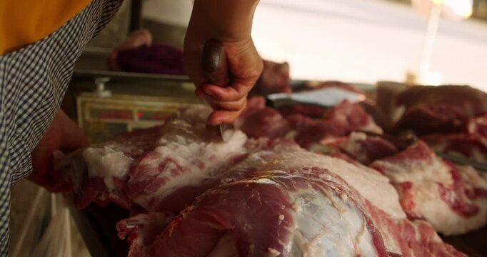 A pork vendor cuts raw meat. The picture shows a typical meat preparation process at a local market: cutting pork into parts for sale. Hanoi, Vietnam - July 17, 2024: