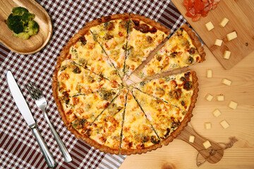 Homemade vegetable quiche with broccoli and cheese on wooden table setting