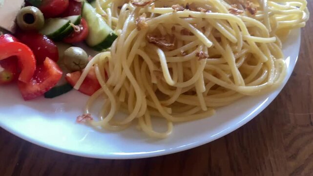 Pasta with a slice of fried turkey and a salad made from tomatoes, cucumber, red pepper, feta, and olives
