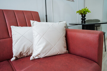 In a cozy living room, there is a vibrant red couch adorned with two stylish white pillows placed...