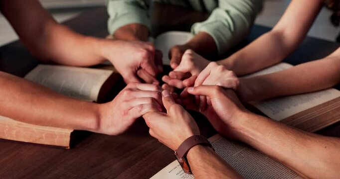 Praying, holding hands and people with bible, church and Christian with faith in God or holy spirit. Prayer group, together and worship with scripture in chapel, table or belief for religion or Jesus