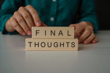 Person s hands arranging wooden blocks spelling out final thoughts