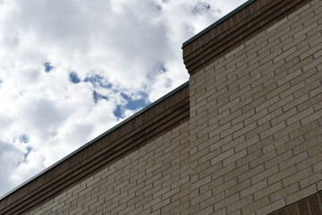 Large shopping mall made of brick. Brick wall, roofline visible, cloudy sky.