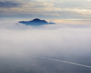 Sun Breaking Through Clouds Over a Foggy Mountain Road in Czechia