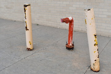 FDC stick out of ground. Parking bollards protect from vehicle strike. One bollard is bent.