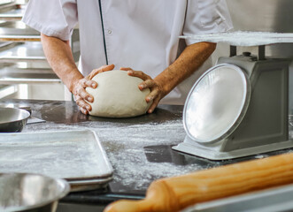 unrecognizable male Baker kneading dough in a bakery kitchen