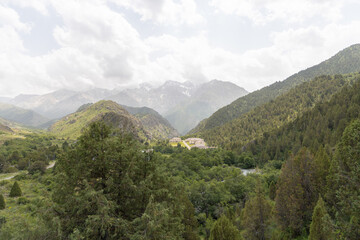 Wide-angle view of Sayram Ugam mountains in light summer haze. Soft light and peaceful atmosphere of distant peaks.
