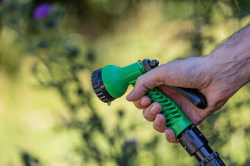 A hosepipe being held but switched off, with a shallow depth of field